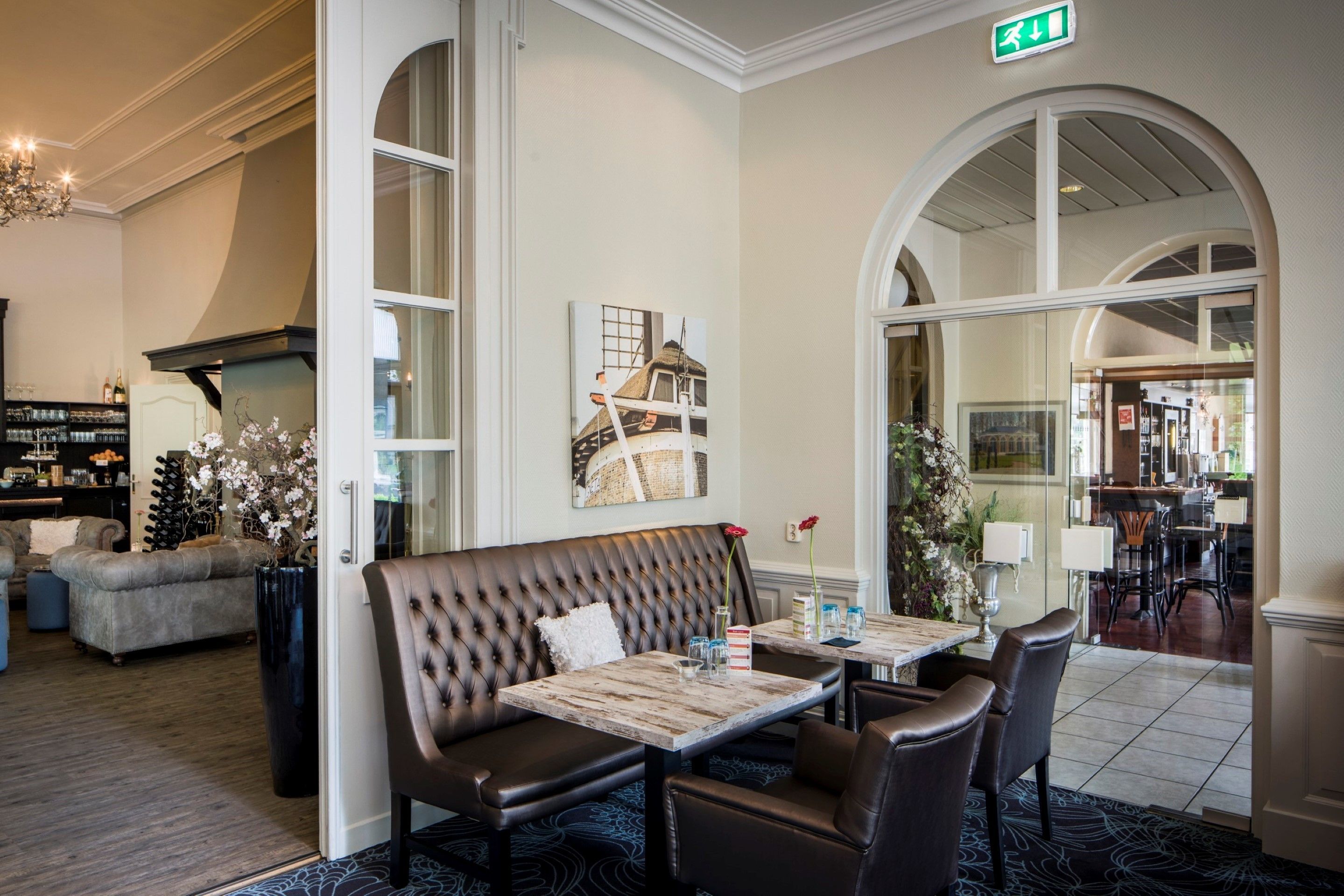 A dining area with a wooden table and leather chairs, a cushioned bench, and a painting on the wall.