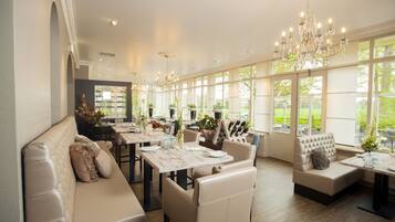 Un comedor amplio con techos altos, candelabros y ventanas grandes que ofrecen vistas al exterior.