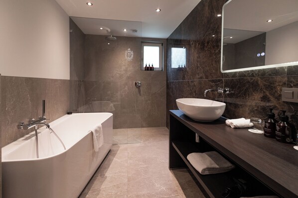 Une salle de bain moderne avec une baignoire sur pieds, un grand miroir et un meuble-lavabo avec un évier et des articles de toilette.