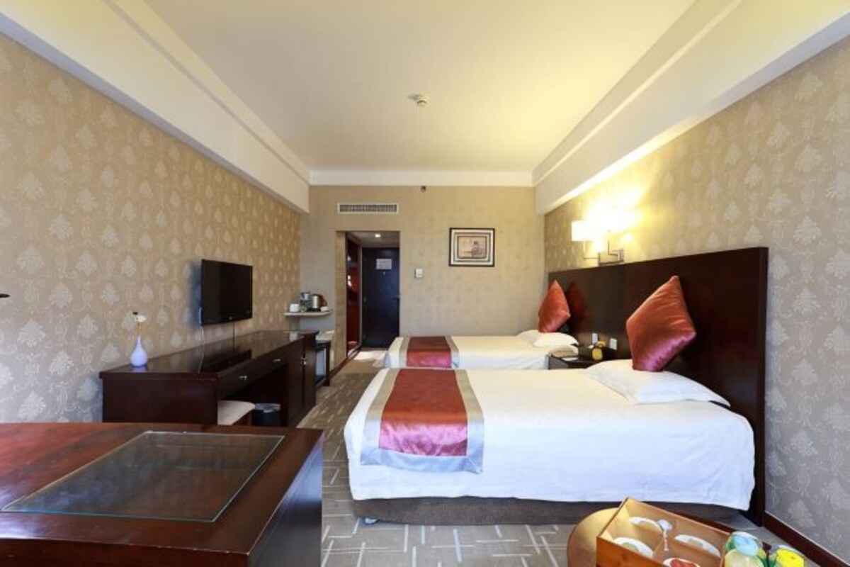 Una habitación de hotel con dos camas, un escritorio, televisión y minibar.