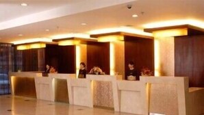 A reception area with multiple counters, each with a person seated behind. - Beijing Hepingli Hotel (Beijing)