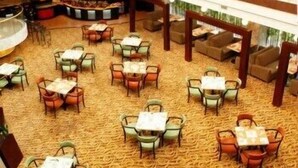 A dining area with tables and chairs arranged in a circular pattern on a patterned carpet. - Beijing Hepingli Hotel (Beijing)