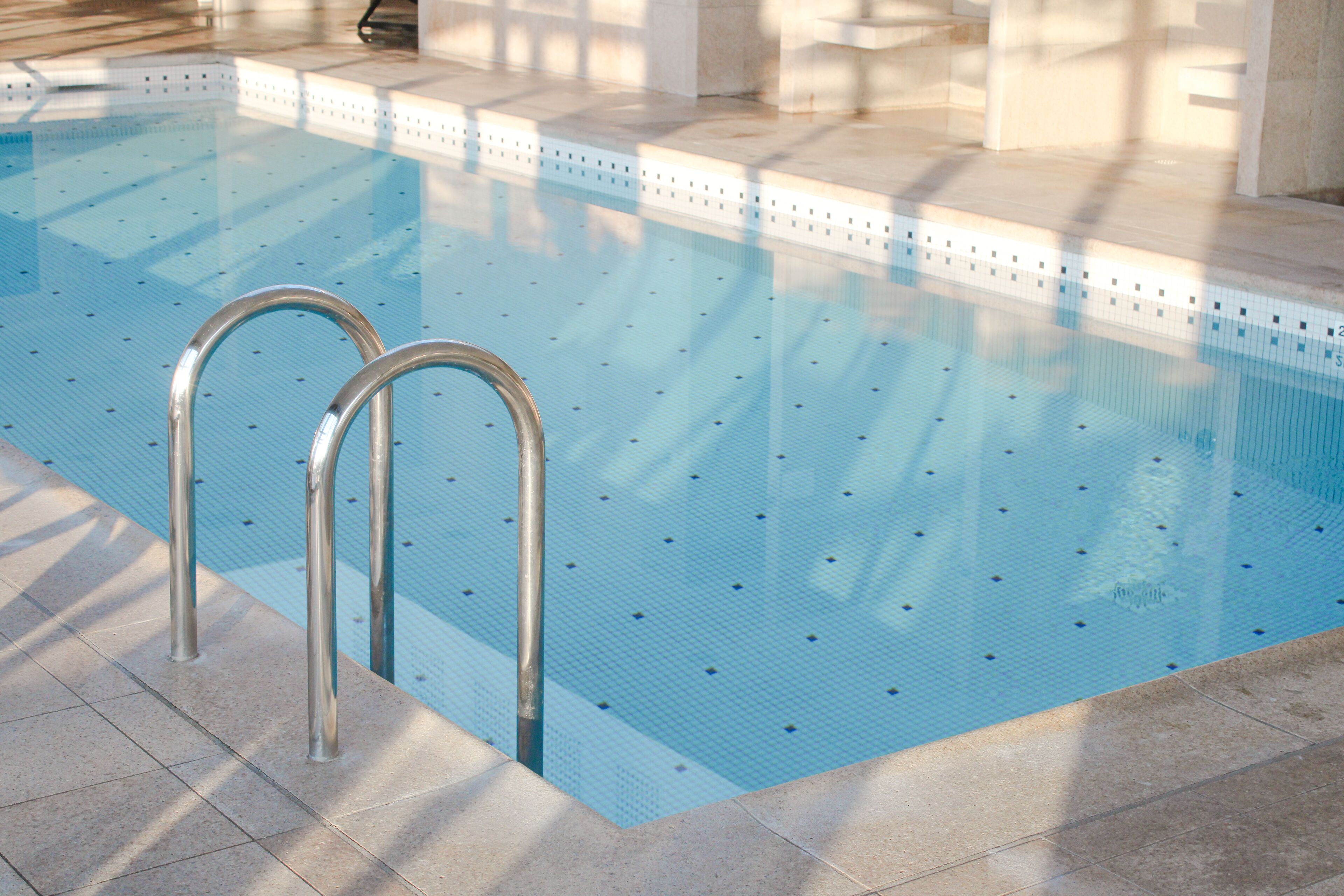 Una piscina con barandillas metálicas y un borde empedrado.