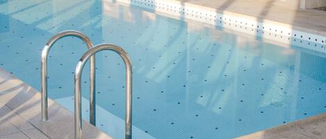 Una piscina con barandillas metálicas y un borde empedrado.
