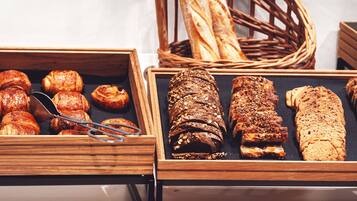 A variety of baked goods displayed in wooden trays and baskets, including pastries and bread.
