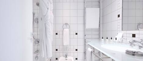 Un bany modern amb rajoles blanques, un vàter, un lavabo amb mirall i moltes tovalloles.