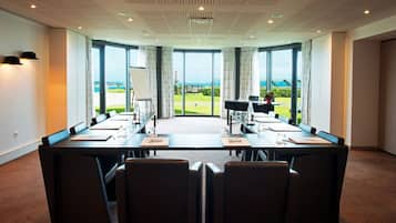 A conference room with a large table, chairs, and a view of the sea.
