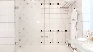 Un baño moderno con cabina de ducha de vidrio, tocador de vidrio y una toalla blanca colgada en la pared.