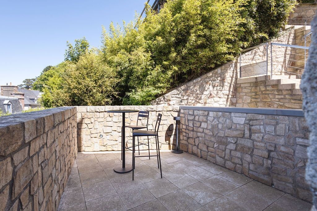 An outdoor patio with stone walls, a table, and two chairs.