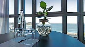 Una mesa con un tarro de cristal que contiene una planta, una botella y un vaso de agua.