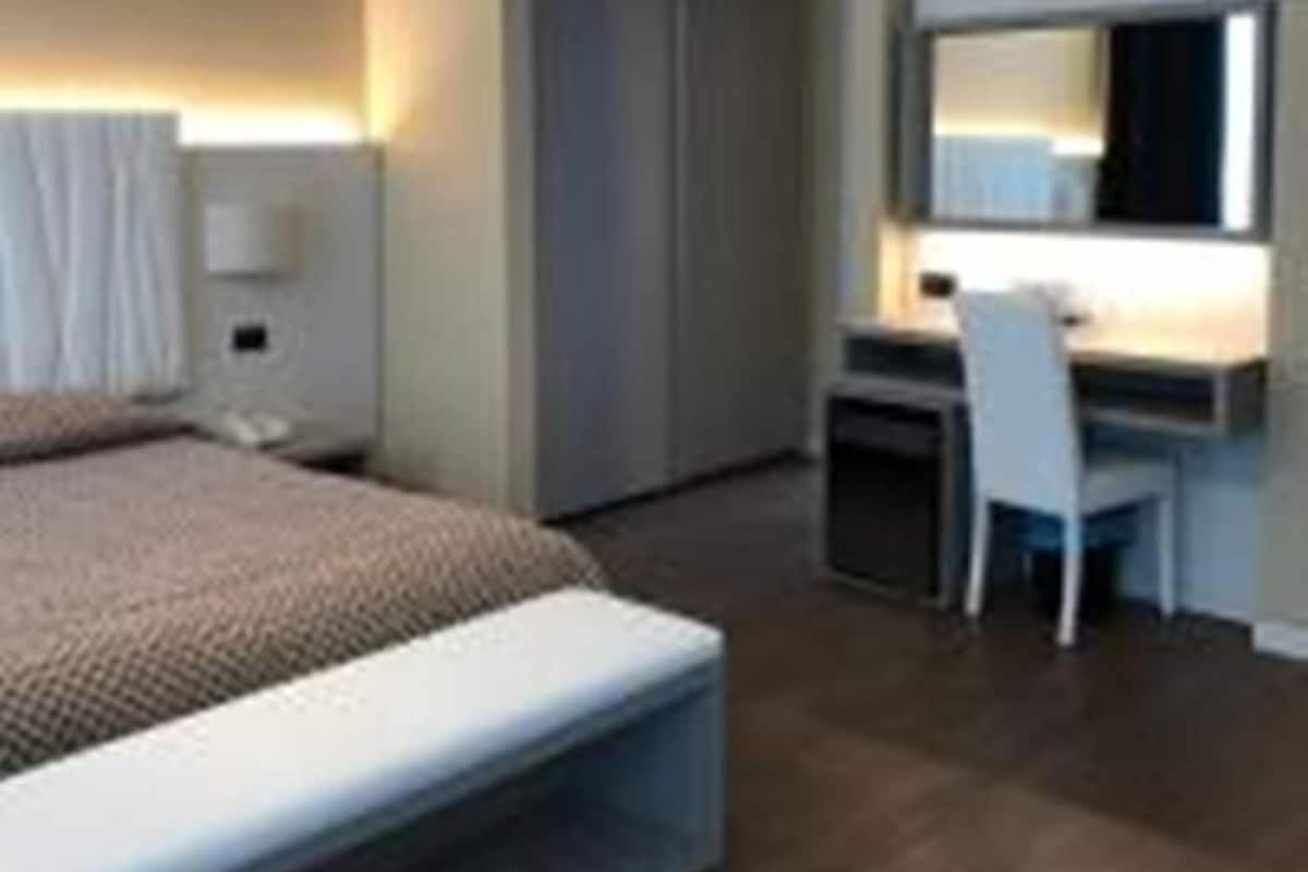A modern hotel room with a bed, desk, and chair.