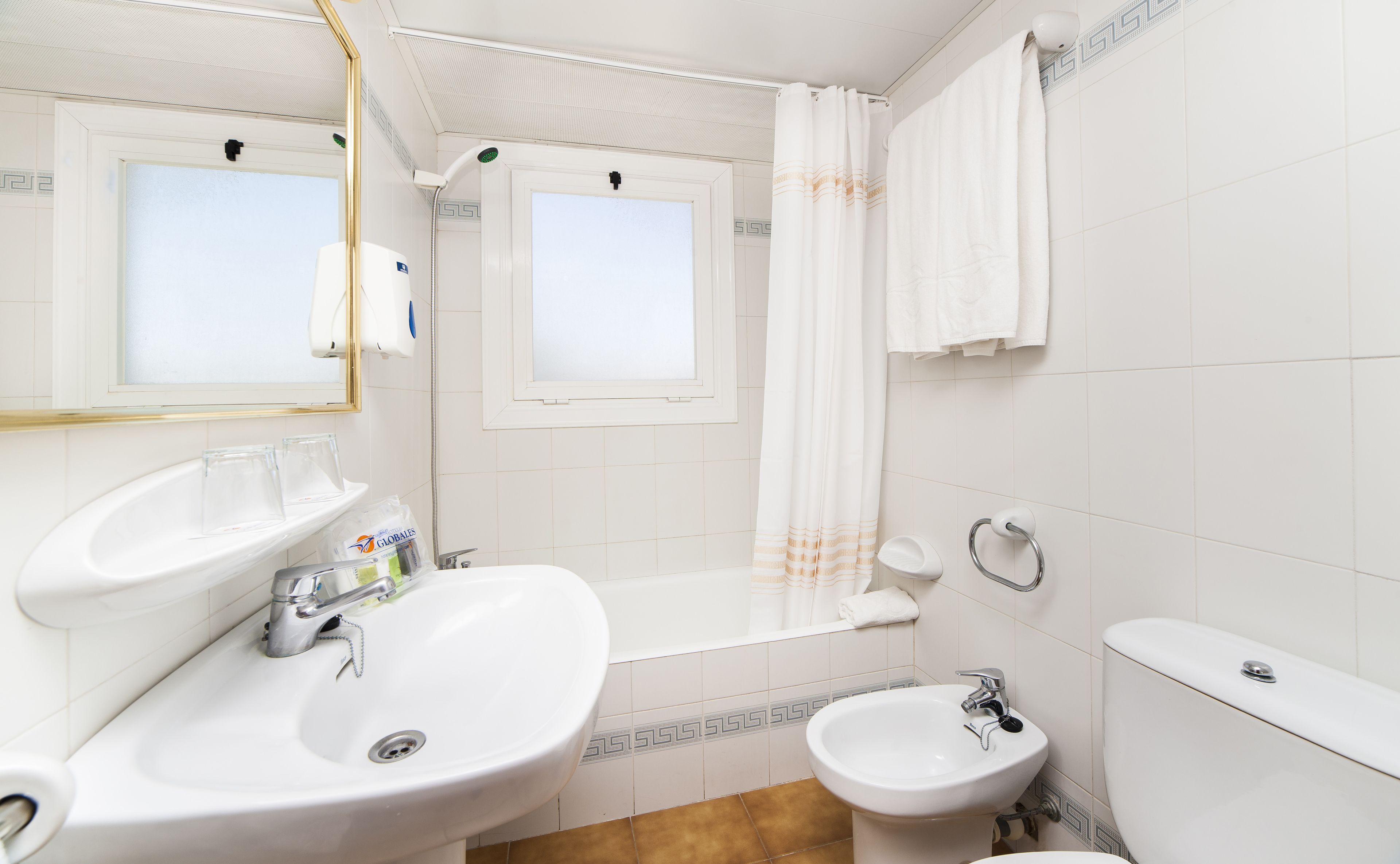 Un baño con lavamanos, bidé, inodoro y ducha.
