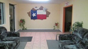 Un hall d’entrée orné d’une fresque représentant le drapeau du Texas, avec deux canapés, un ventilateur de plafond et des plantes en pot.