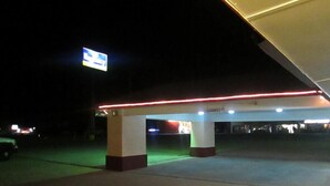 Une station-service la nuit, avec une enseigne bien visible indiquant « Débarras : allée 8 ».