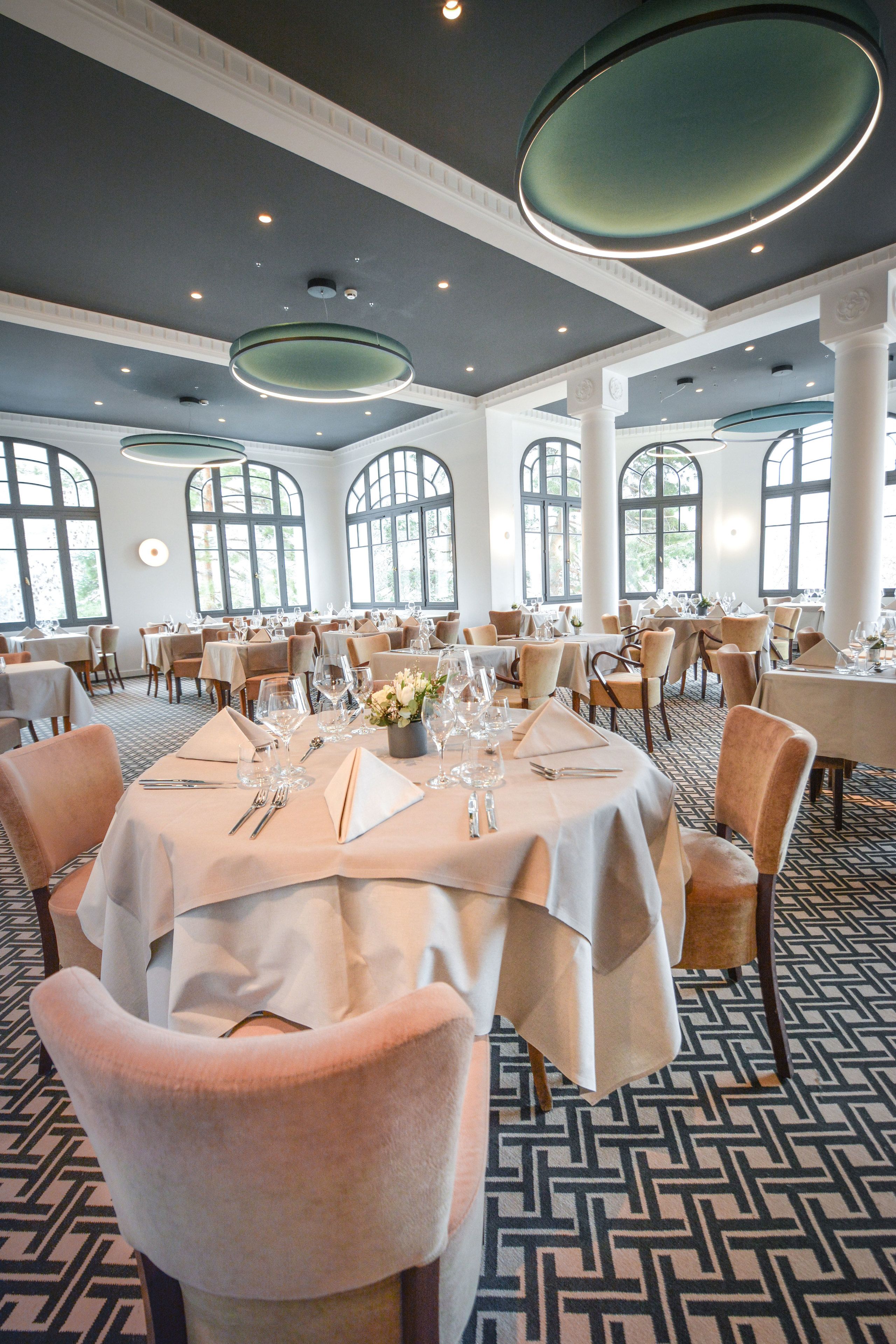 Un vaste espace dédié à la salle à manger, avec des tables rondes, des nappes blanches et des chaises confortables.