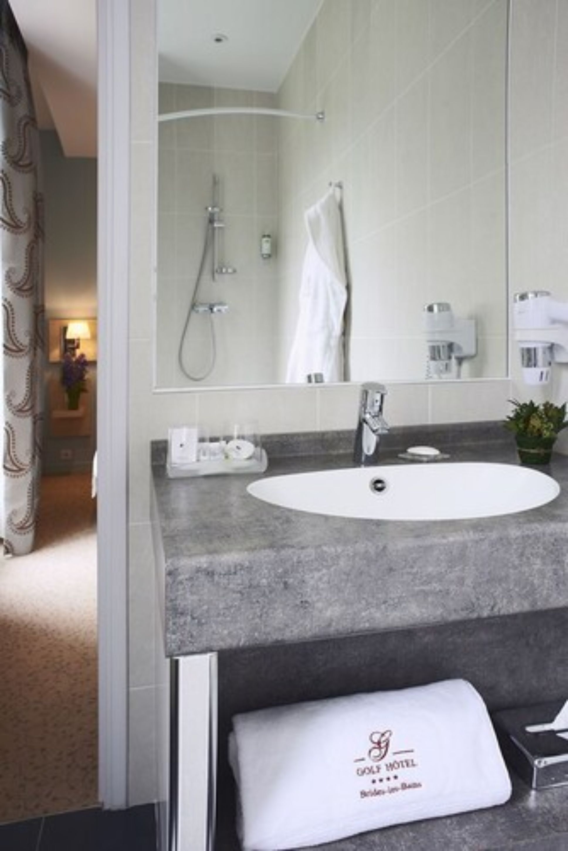 A modern bathroom with a large mirror, a white sink, and a shower.