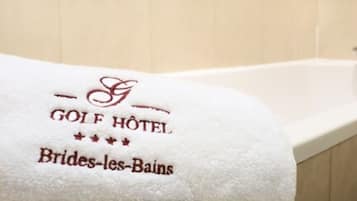 A white towel with embroidered text reading "GOLF HOTEL Brides-les-Bains" on a bathtub.