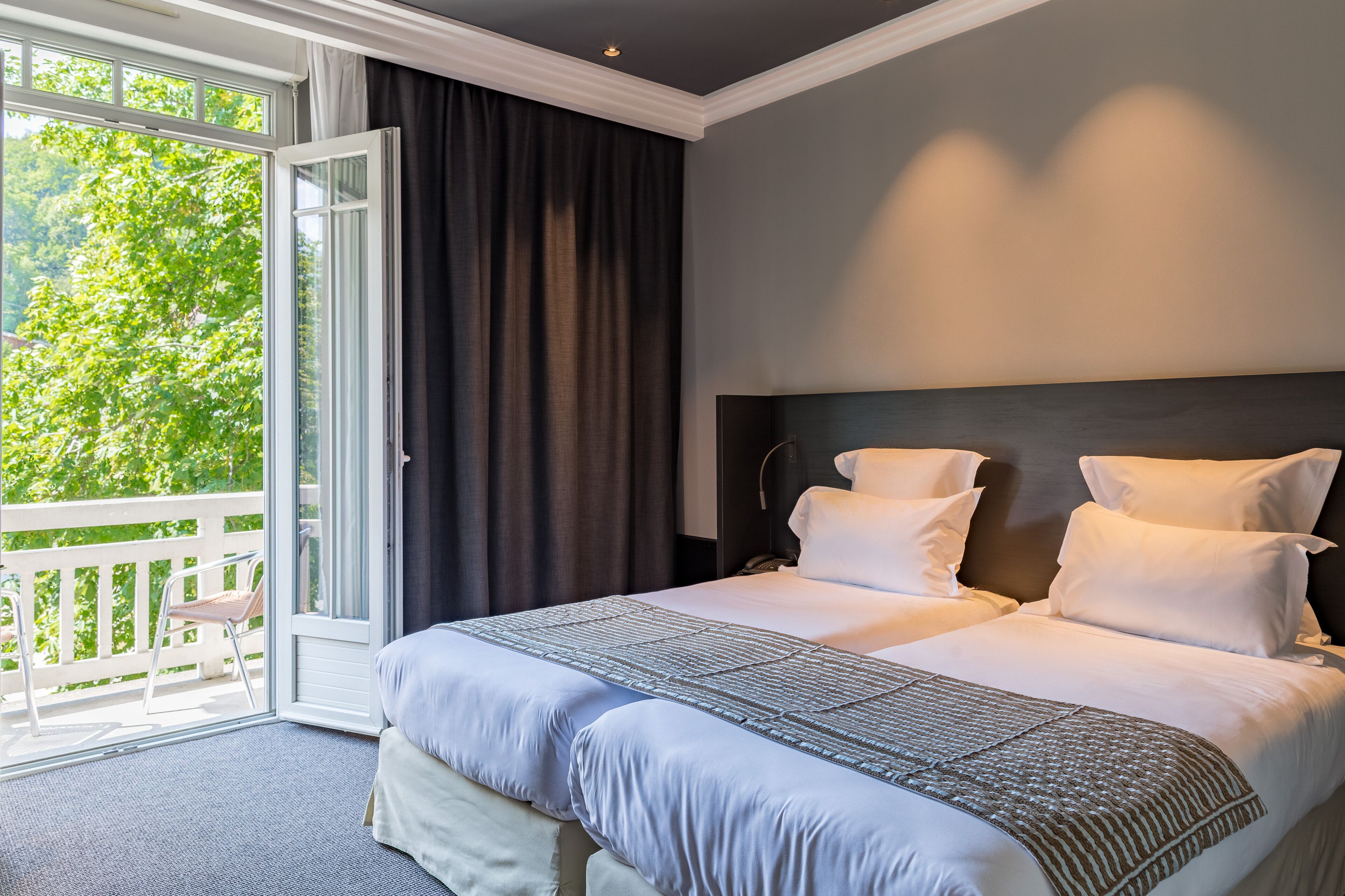 Una habitación de hotel con una cama grande, un balcón y vistas a árboles.