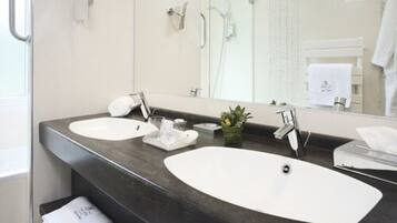 Ein modernes Badezimmer mit zwei Waschbecken, einem großen Spiegel und einer Duschkabine.