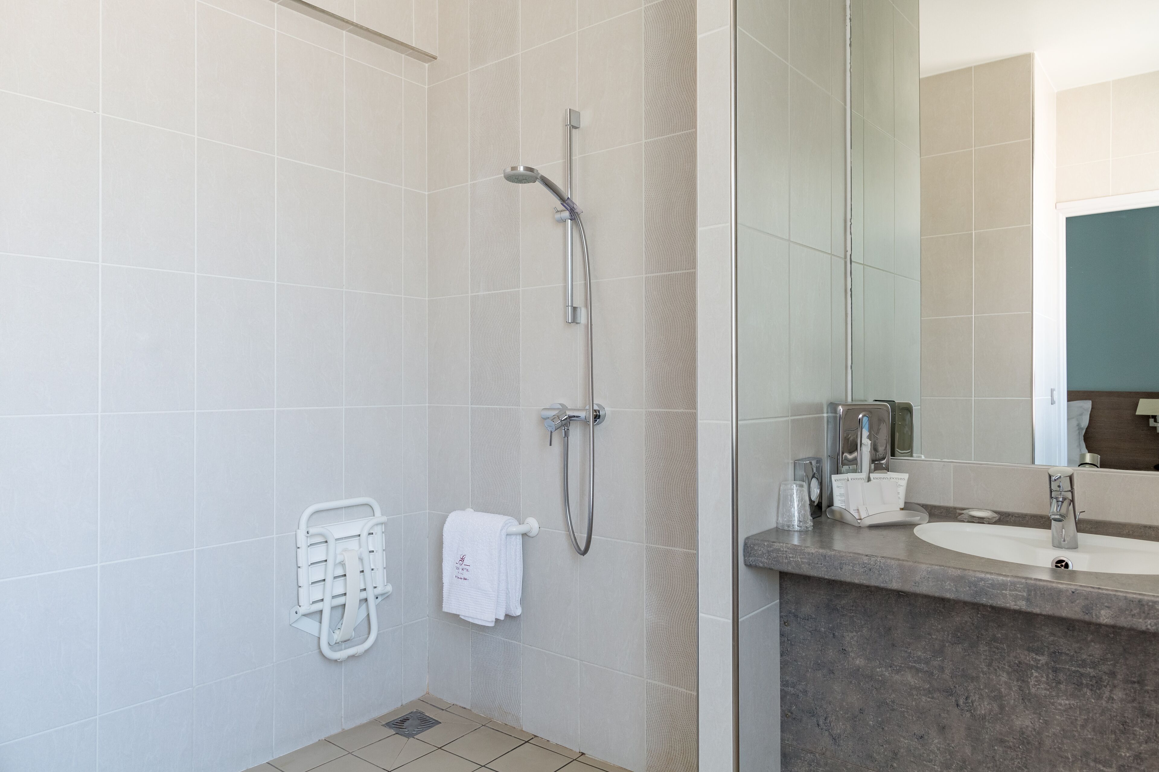 A modern bathroom with a shower, a sink, and a towel rack.