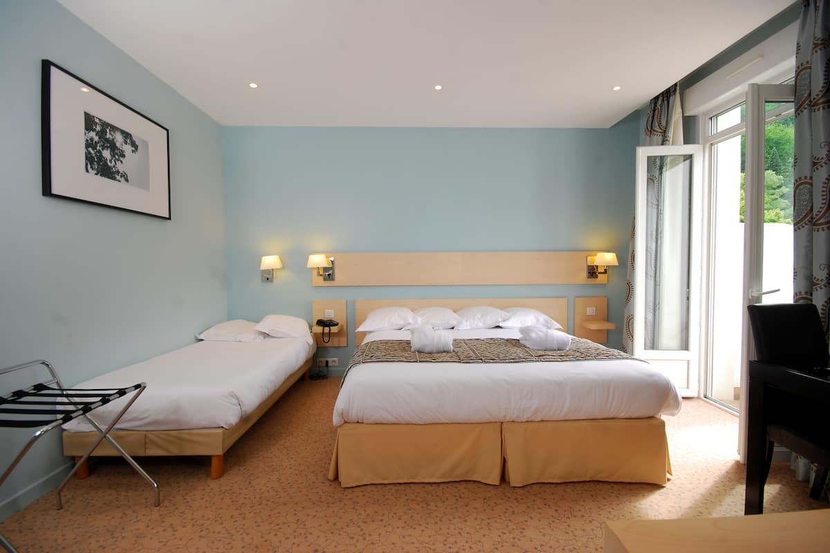 Ein Hotelzimmer mit zwei Einzelbetten, einem Doppelbett, einem Klavier und einem großen Fenster mit Vorhängen.
