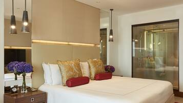 A modern hotel room with a large bed, a nightstand with a clock, and a mirror.