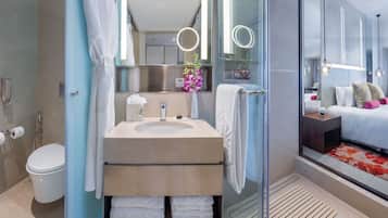 A modern bathroom with a glass-enclosed shower, a sink with a towel rack, and a toilet.