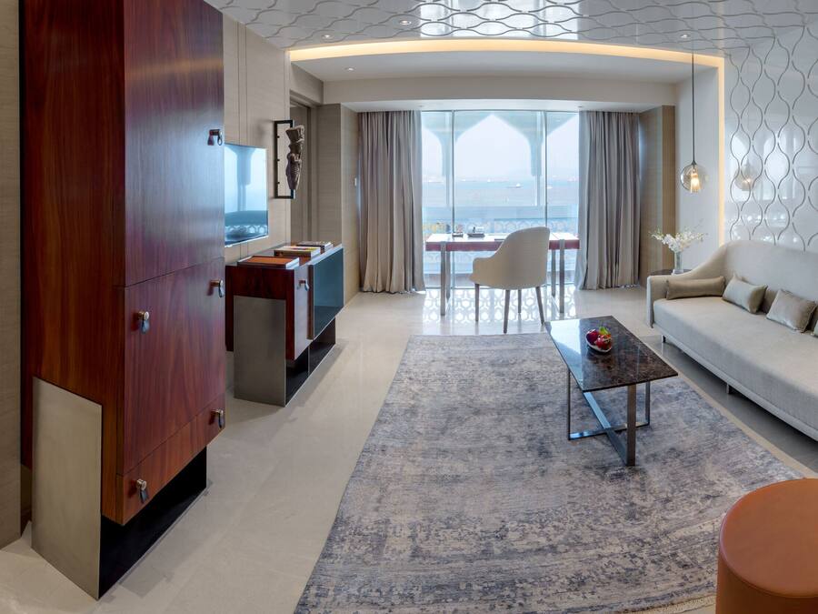 Ein modernes Hotelzimmer mit einer Couch, einem Sessel und einem Essbereich mit Blick.