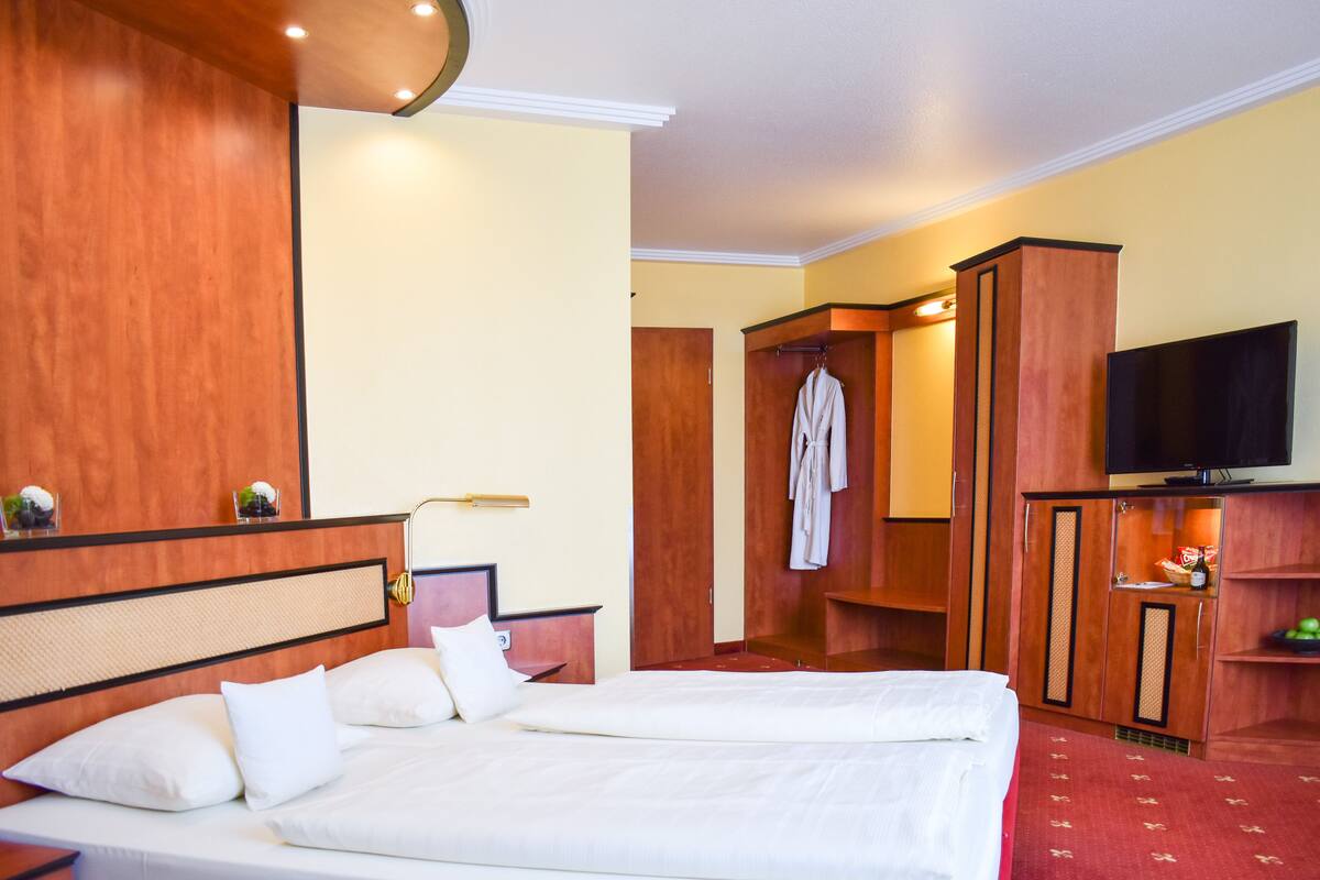 Une chambre d’hôtel avec un grand lit, une télévision et une armoire.