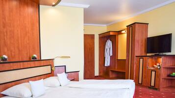 Una habitación de hotel con una cama grande, un televisor y un armario.