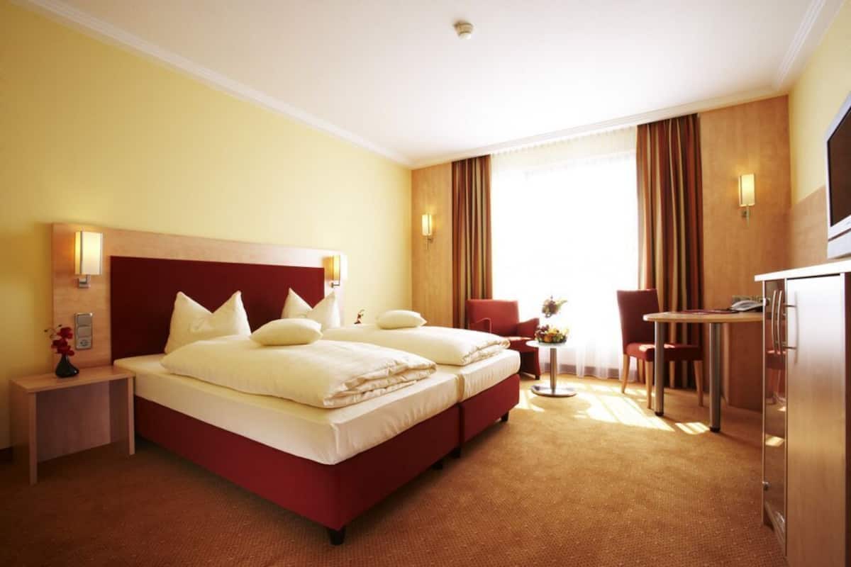 Une chambre d’hôtel avec un grand lit, un bureau, une chaise et un téléviseur.