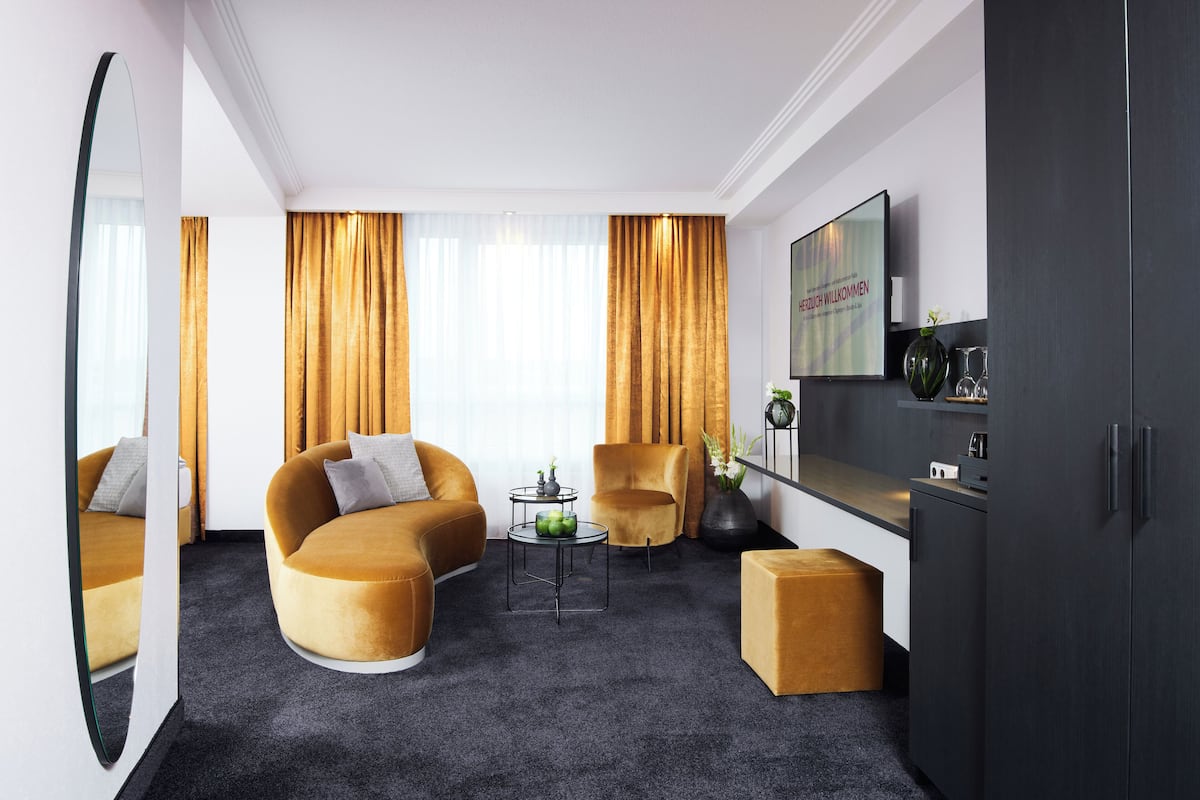 Un salon moderne comprenant un canapé, un fauteuil, une table basse et un téléviseur fixé au mur.