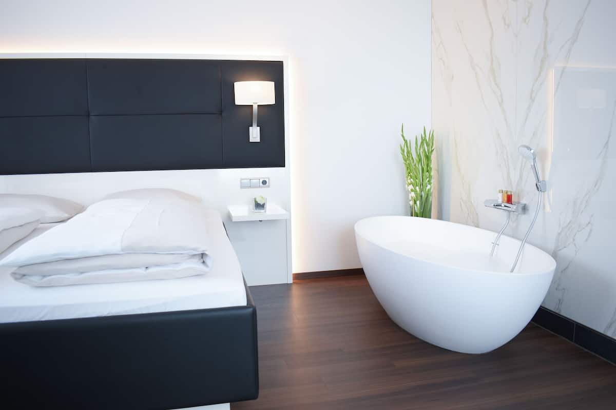 Une chambre à coucher moderne avec un grand lit, une table de chevet et une baignoire sur pieds.