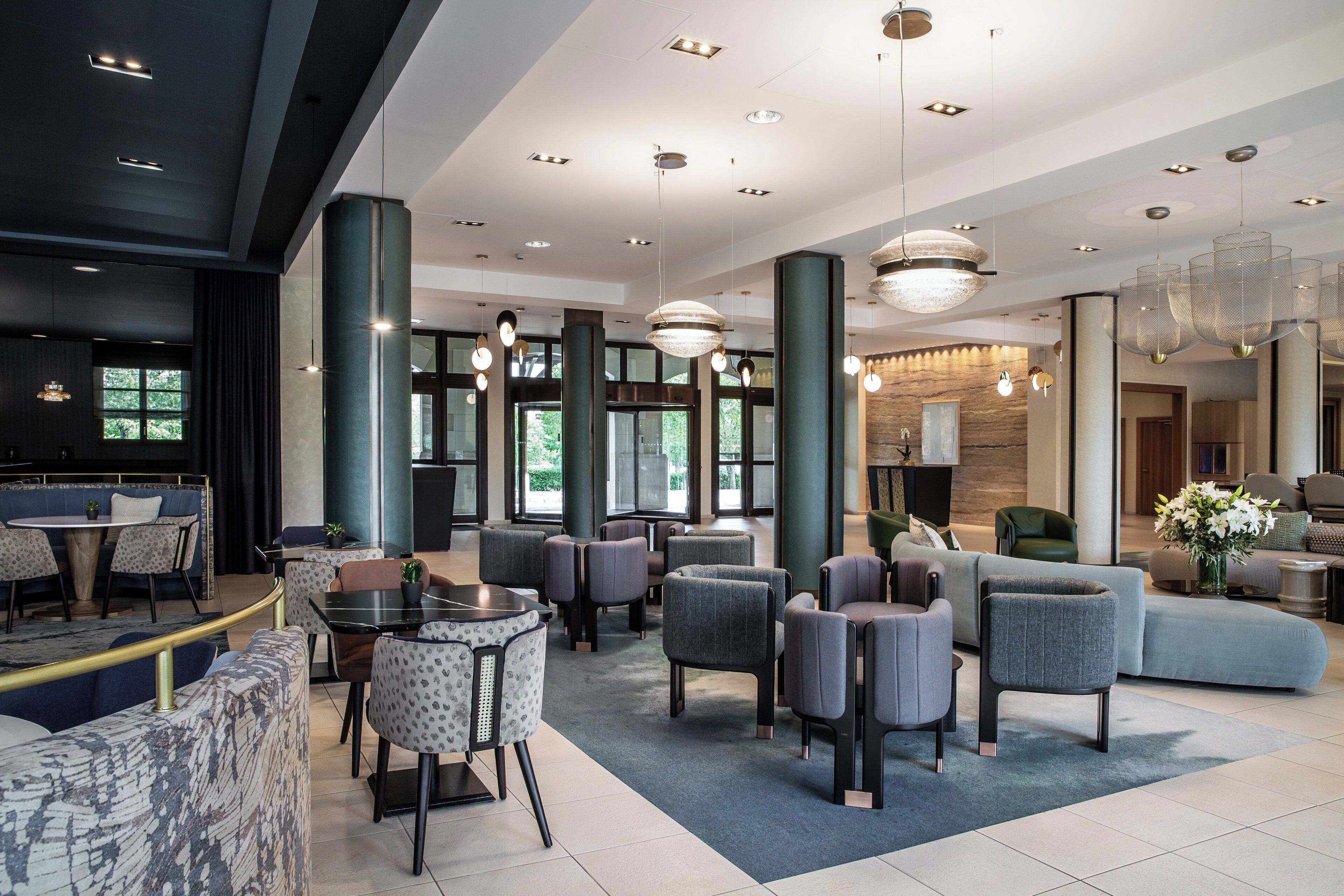 A modern hotel lobby with seating areas, a reception desk, and large windows allowing natural light.