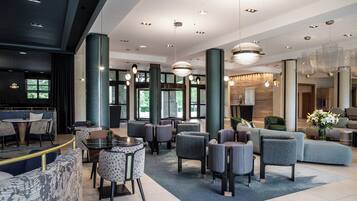 A modern hotel lobby with seating areas, a reception desk, and large windows allowing natural light.