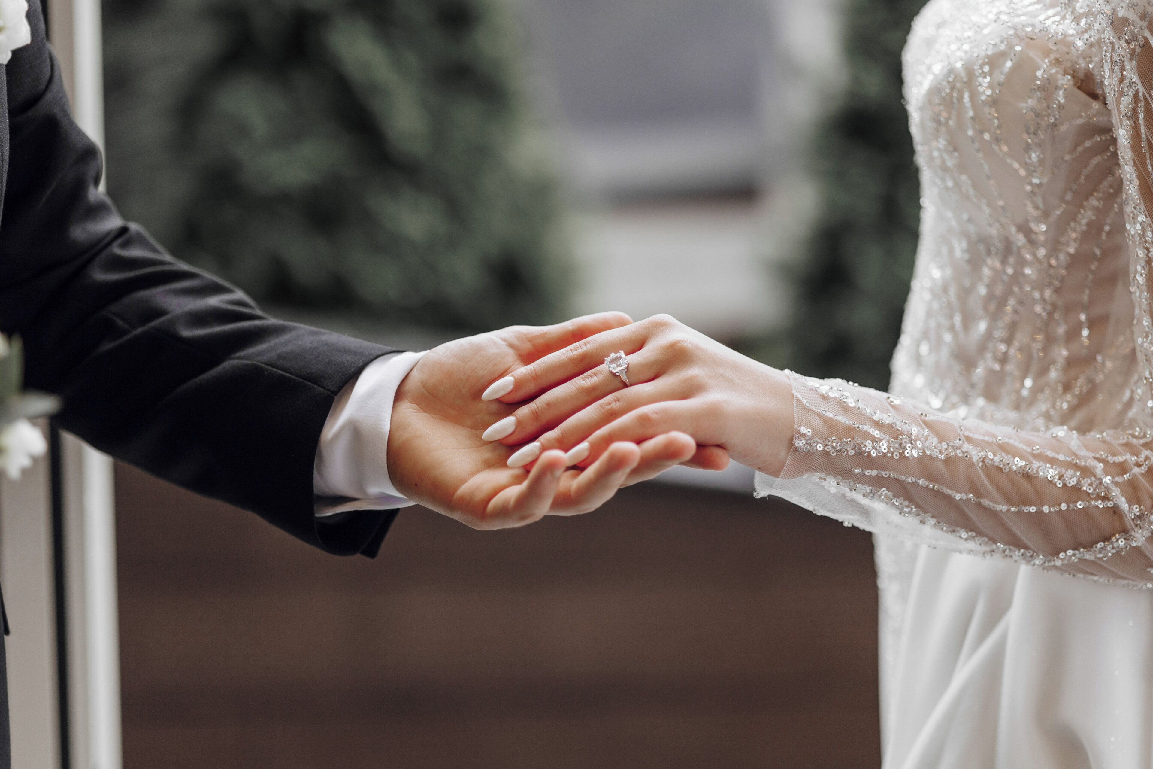 A close-up of a hand holding another hand, with a wedding ring visible.