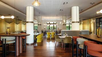 Un restaurant spacieux avec de hauts plafonds, plusieurs espaces de restauration et une variété de styles de tables et de chaises.