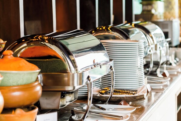 A buffet setup with multiple self-service food stations, including hot and cold food options, arranged in a row.