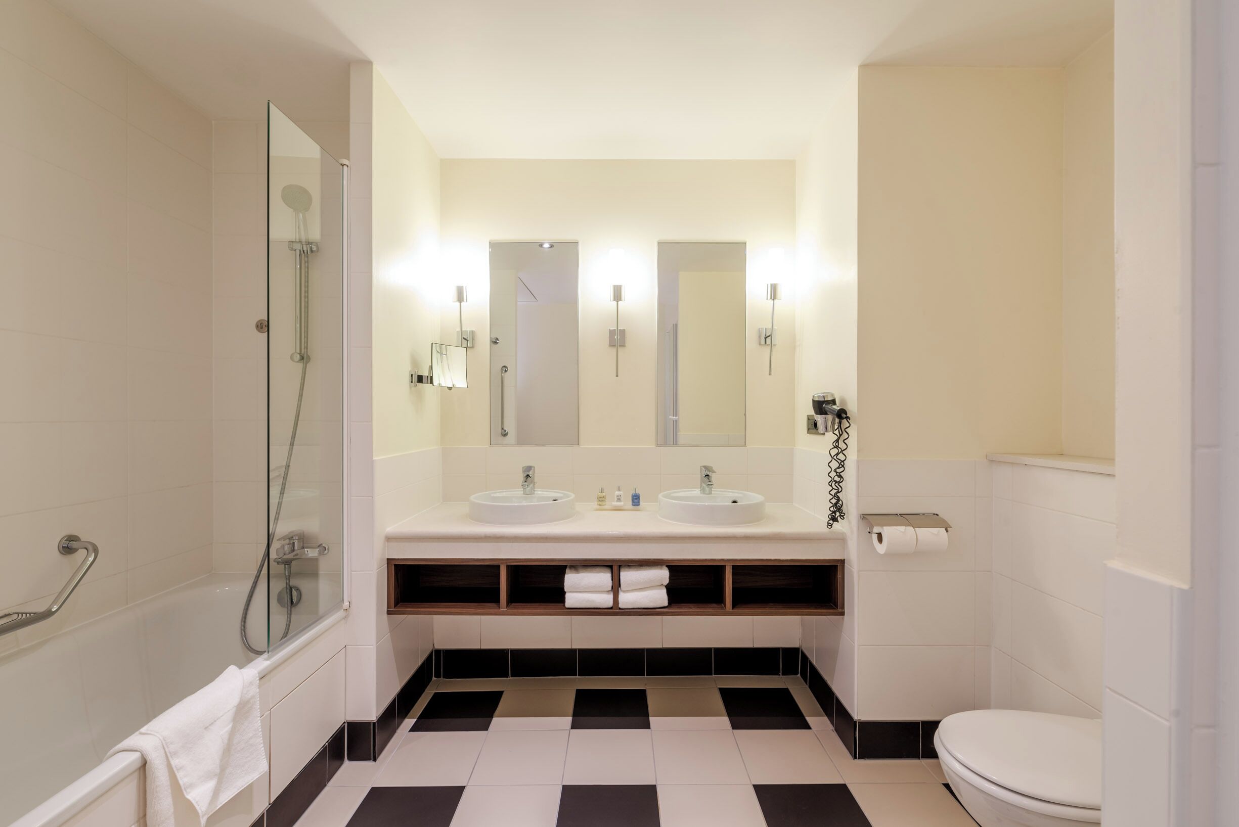 Une salle de bain moderne équipée d’une baignoire, d’une douche, d’un lavabo avec un miroir et de toilettes.