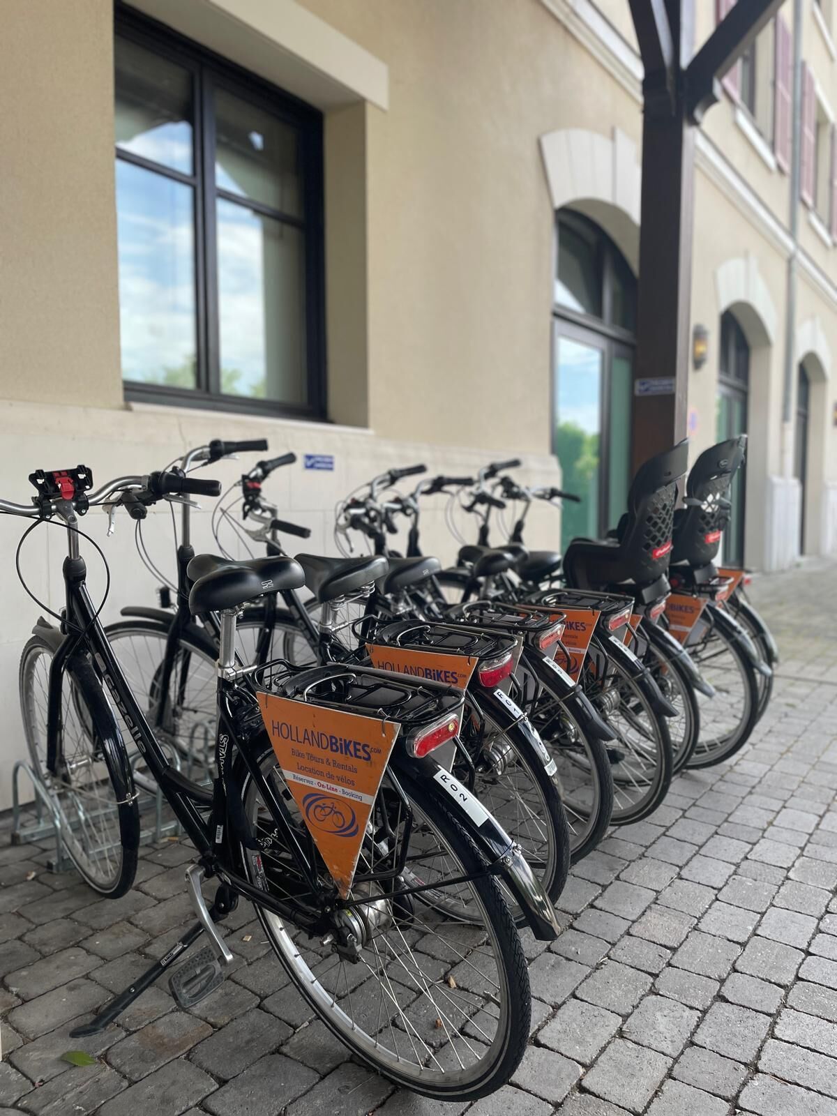 Una filera de bicicletes aparcades davant d'un edifici amb un cartell que indica lloguer de bicicletes.