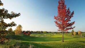 A golf course with a flag on the green, surrounded by trees with autumn leaves. - Crowne Plaza Paris Marne-la-Vallée by IHG (Magny-le-Hongre)