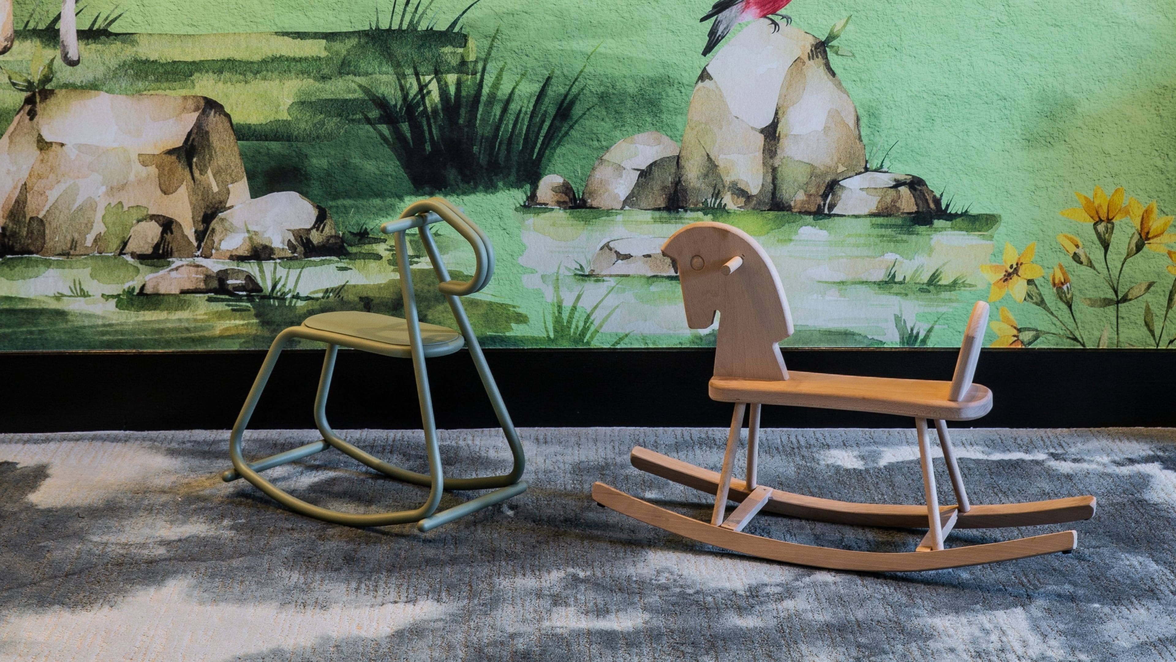 A rocking chair and a stool in front of a painting.