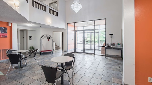 A spacious indoor area with a high ceiling, a chandelier, a staircase, and a large glass door leading outside. - Motel 6 Lawrence, KS (Lawrence)
