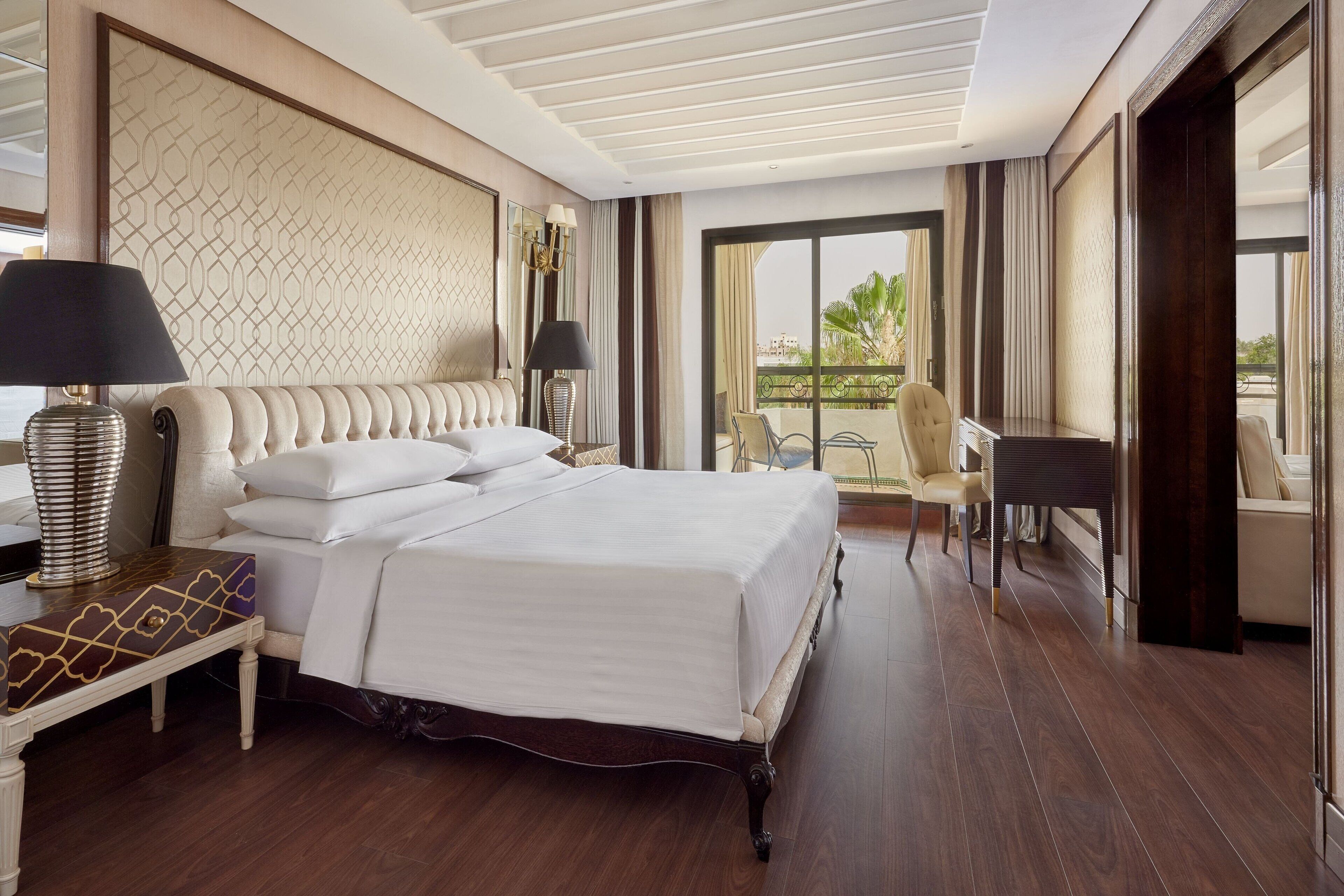 Une chambre d’hôtel avec un grand lit, un bureau, une chaise et un balcon avec vue.