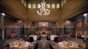 Un comedor lujoso con candelabros ornamentados, paredes con diseños y decoración tradicional marroquí.