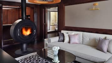 Ein modernes Wohnzimmer mit Kaminofen, einem weißen Sofa mit Zierkissen, einem Glastisch und einem gemusterten Teppich.