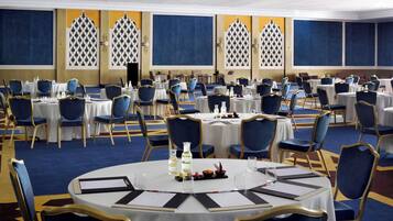 A conference room with round tables, blue chairs, and a carpeted floor.