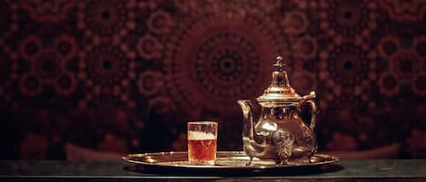 A traditional tea set with a teapot and cup on a tray, placed on a table with a patterned tablecloth.