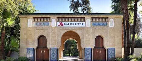 A Marriott hotel entrance with an ornate archway, tiled walls, and a paved pathway leading to the doors.