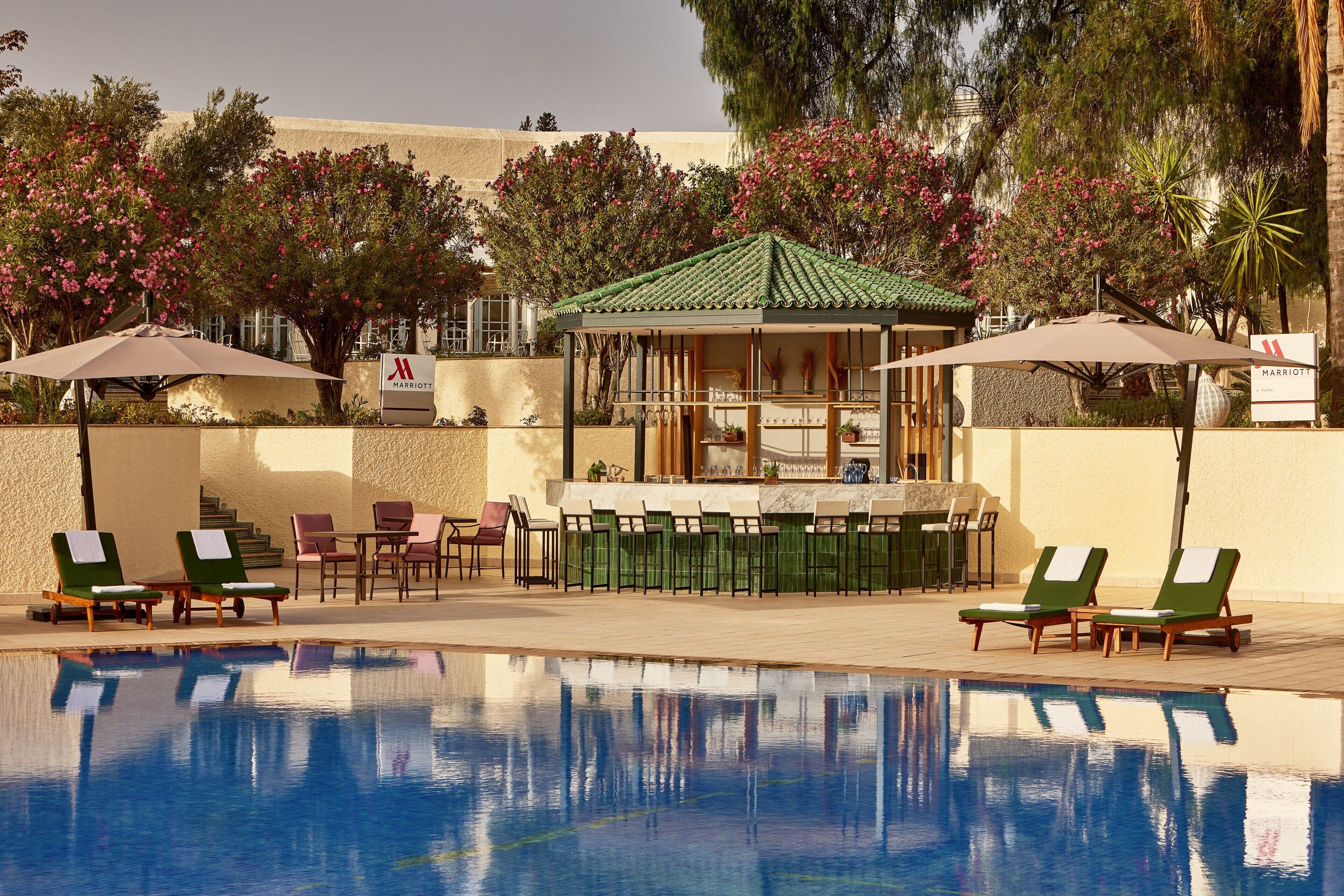 A pool area with lounge chairs and umbrellas, a bar, and a gazebo.